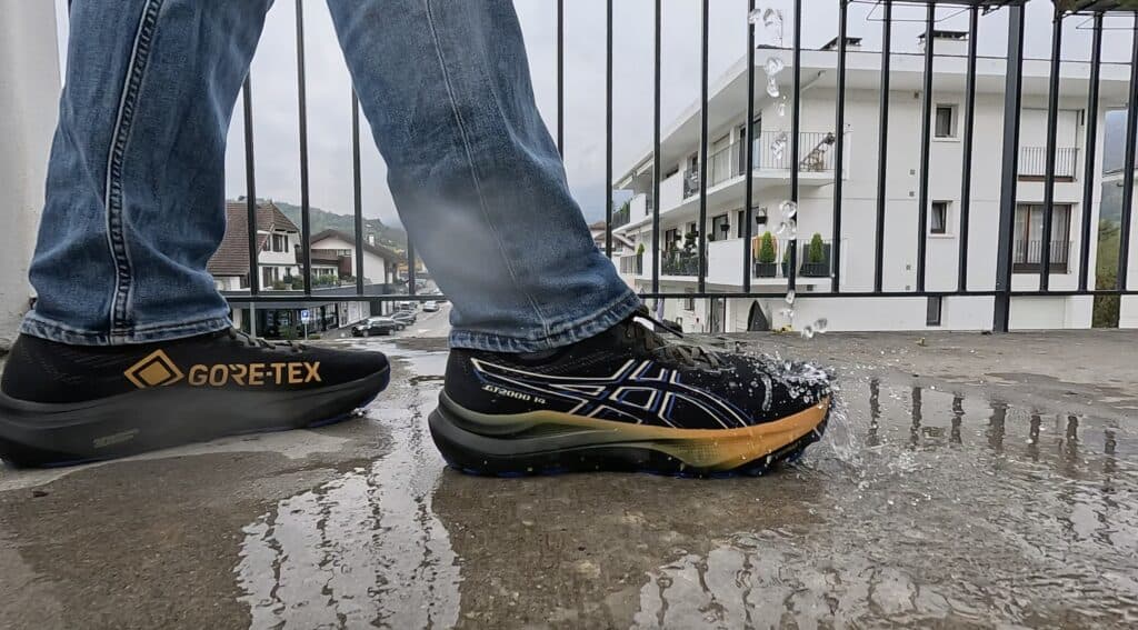 ASICS GT-2000 14 Gore-Tex shoes being tested in heavy rain and puddles, highlighting stability features and trail-ready grip.